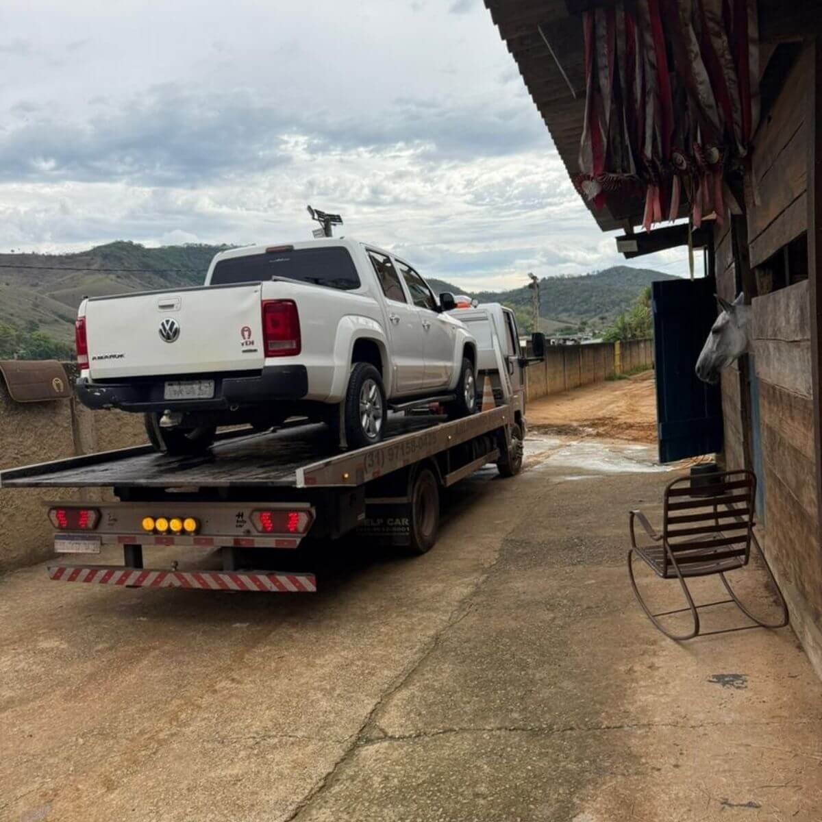 Reboque de caminhonete pickup branca realizado com segurança em estrada de terra.