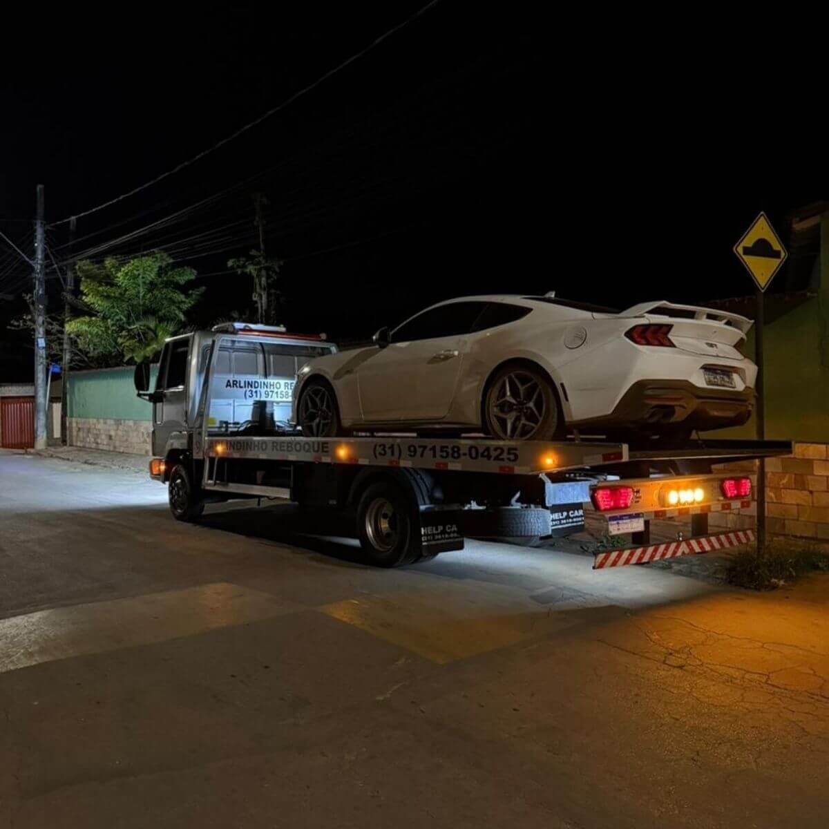 Transporte de carro esportivo de luxo (Camaro branco) realizado com cuidado à noite.