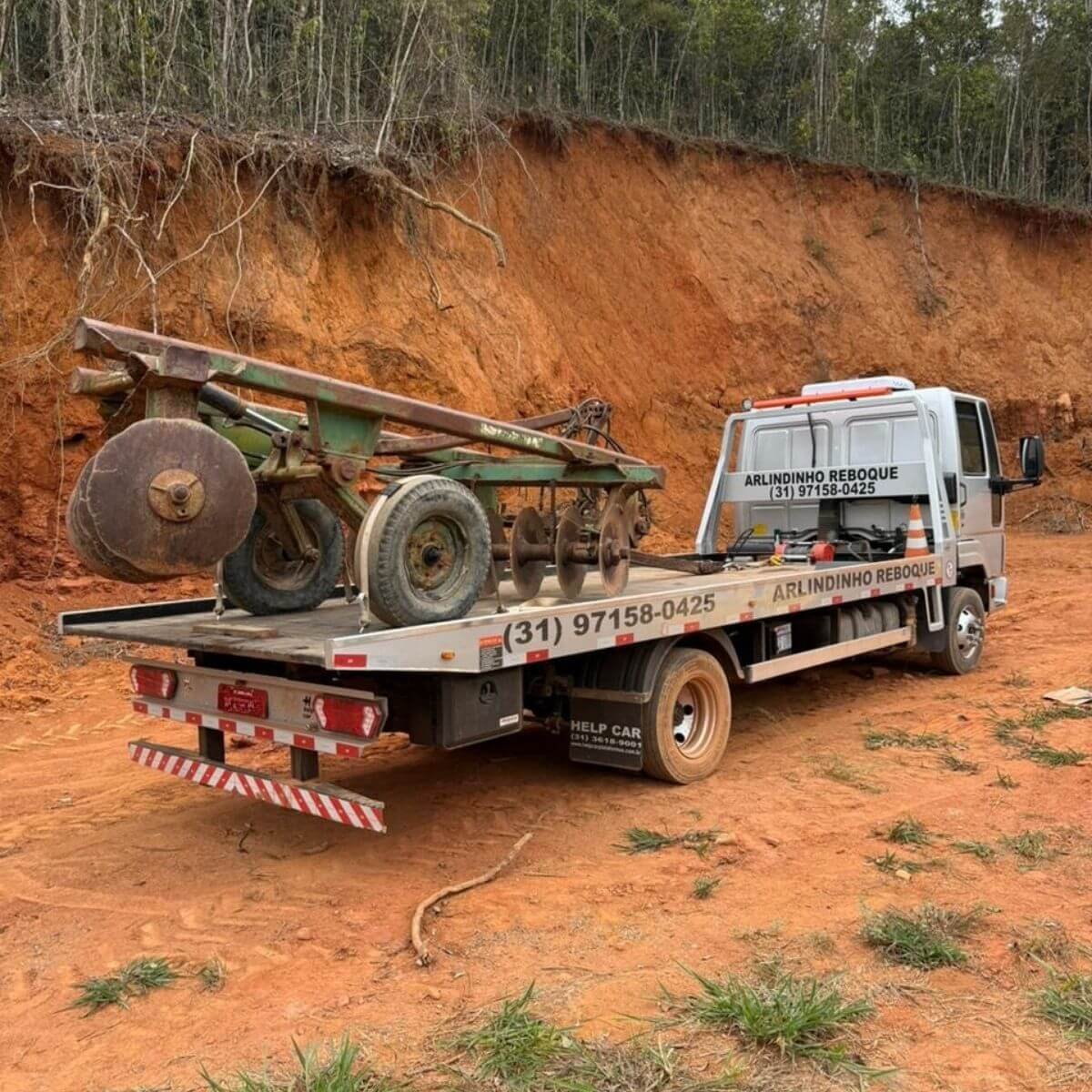 Transporte de implementos agrícolas pesados em caminhão guincho.